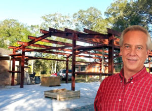 Happy man stands in front of his roomy steel workshop going up.