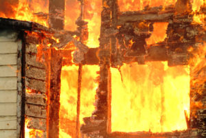 Photo of a flammable wood building on fire.