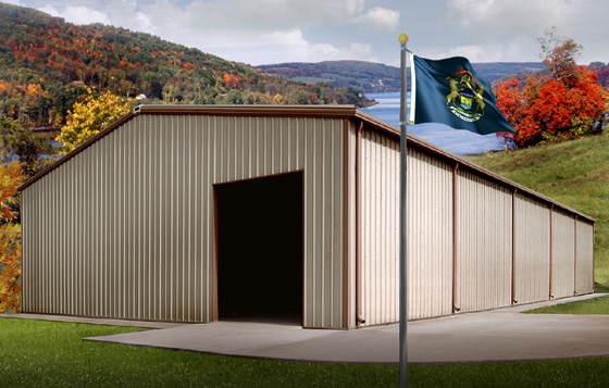 Tan metal building with brown trim on a hillside overlooking a lake in autumn