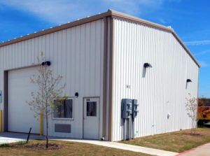 Photo of a white RHINO metal building with tan trim and gutters.