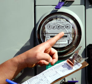 Photo of a hand pointing to a utility meter.