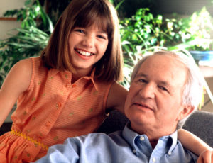 Photo of a smiling granddaughter with her arm around her grandfather's neck.