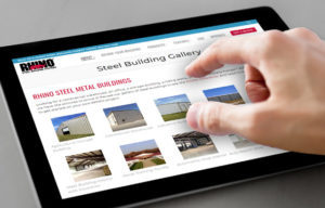 Image of a hand over an electronic tablet displaying the RHINO steel building gallery.