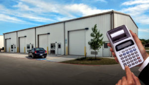 Photo of a metal building with four bays and a man's hand holding a calculator.