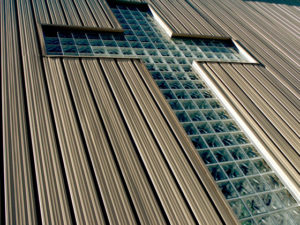 Photo of a huge glass cross set in a steel church building wall.