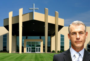 Pastor stands before beautiful metal church building.