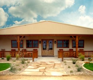 country-style tan steel home with wood trim and covered porch