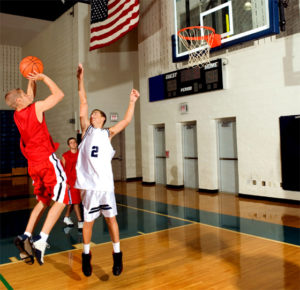 Active students playing basketball in one of the prefab school gyms available from RHINO Steel Building Systems.