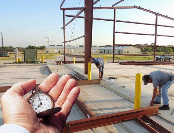 Hand holding timer in front of building construction site