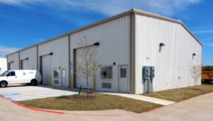 Photo of a white industrial steel building with tan trim.